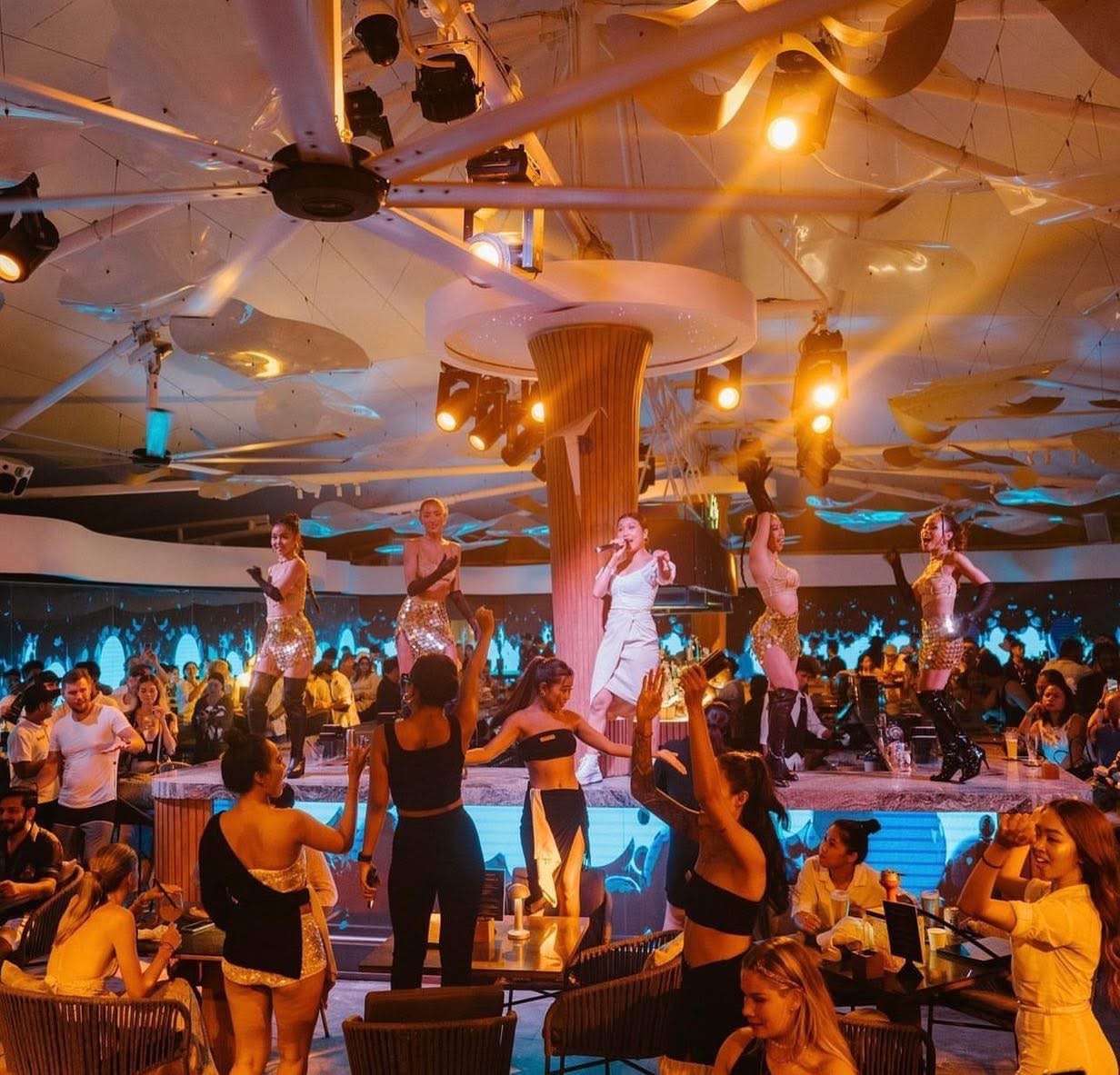 A hospitality venue in the evening, full of guests, with live performance and layered lighting