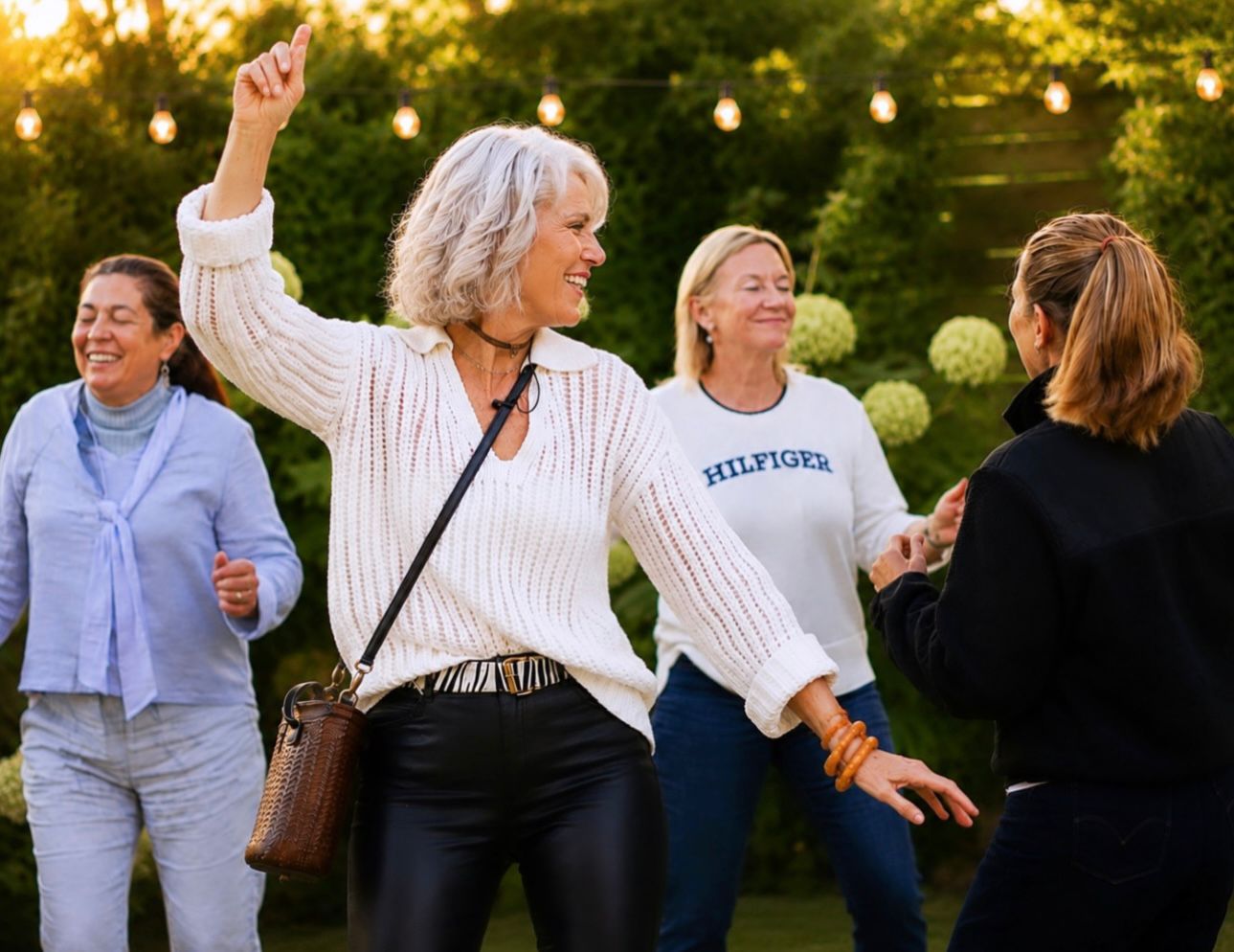 Ros Banksia-Smith laughing with her arm raised at an outdoor gathering