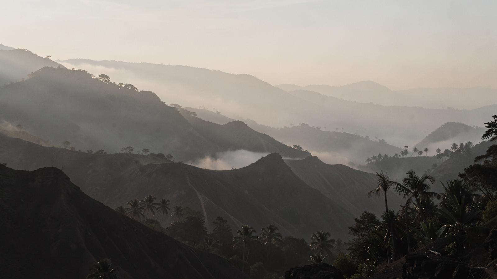 Layered volcanic ridgelines in soft morning mist